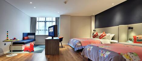 A modern hotel room with a wooden floor, a desk with a computer, two beds with Hello Kitty bedding, a window with curtains, and a view of the city.