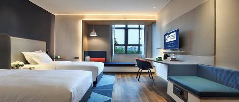 Una habitación de hotel moderna con dos camas, un escritorio, un televisor y vistas a la ciudad.