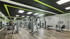 Un gimnasio con diversas máquinas de ejercicio, paredes espejadas y piso estampado.