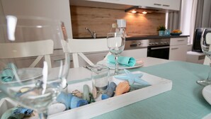 A dining area with a table set for two, featuring a tray with seashells and a starfish, and two wine glasses. - Haus Johanneshorst (Sellin)