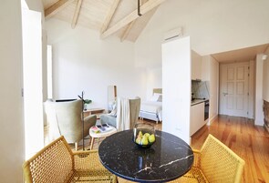 Una sala de estar moderna con una mesa redonda de mármol negro, sillas de mimbre, un sofá y una mesa de comedor con un frutero.