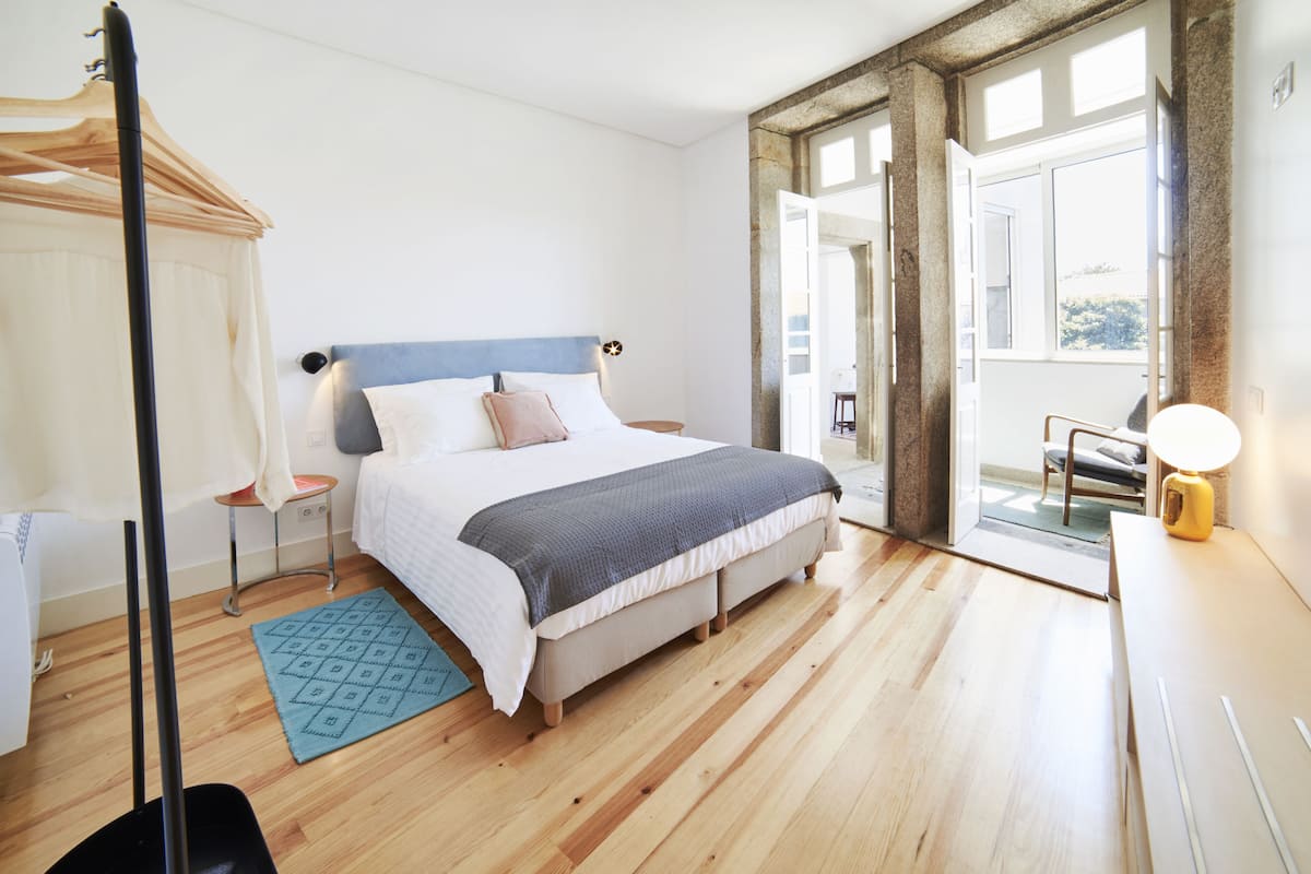 A bedroom with a bed, bedside tables, a nightstand, a window, and a view of the outdoors.