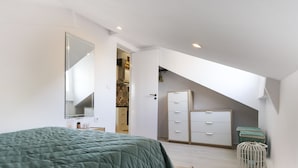 A bedroom with a bed, a wardrobe, a mirror, and a small white basket. - Bairro Alto Views by Homing (Lisbon)