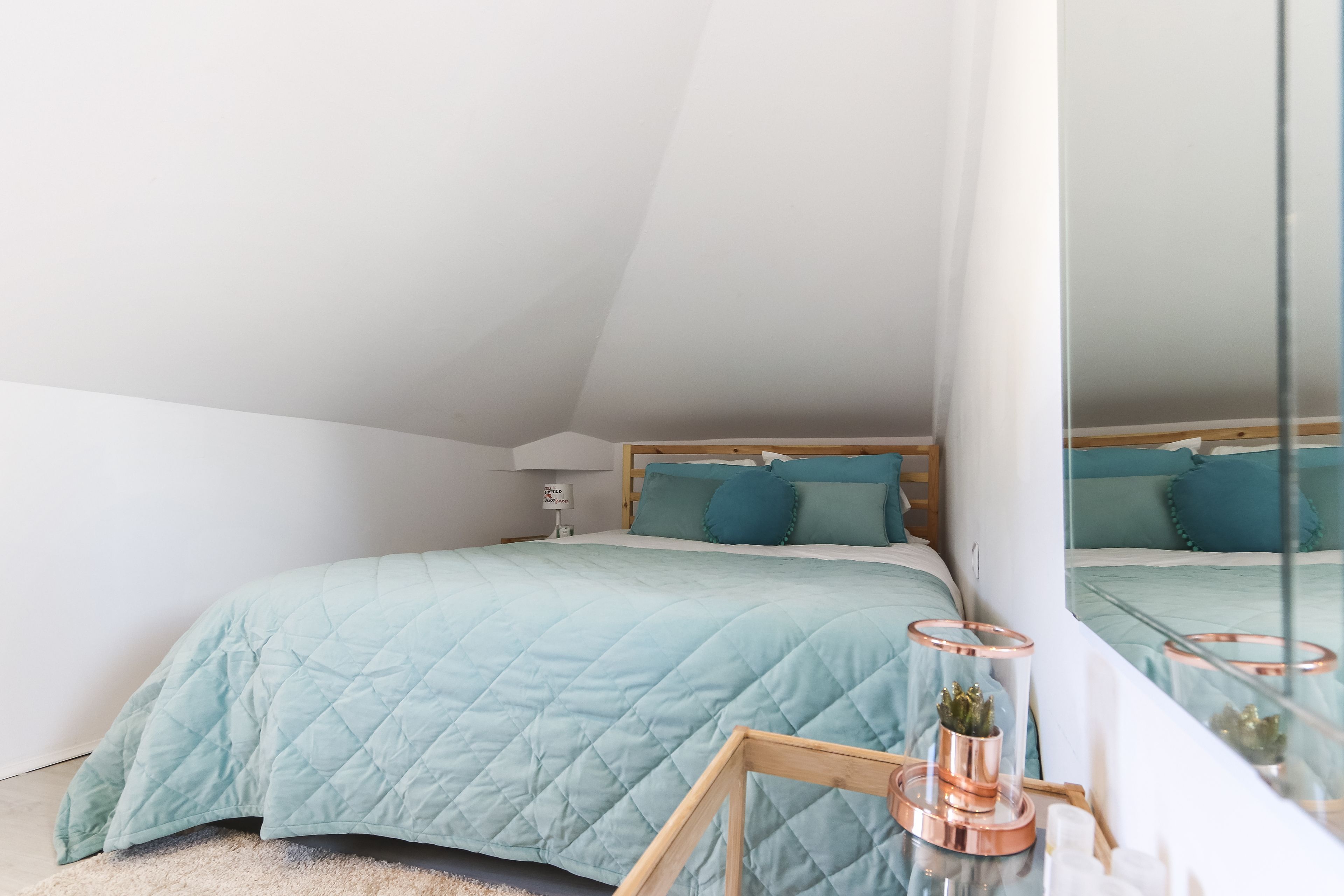 Une chambre à coucher avec un lit, une table de chevet, une lampe et un miroir.