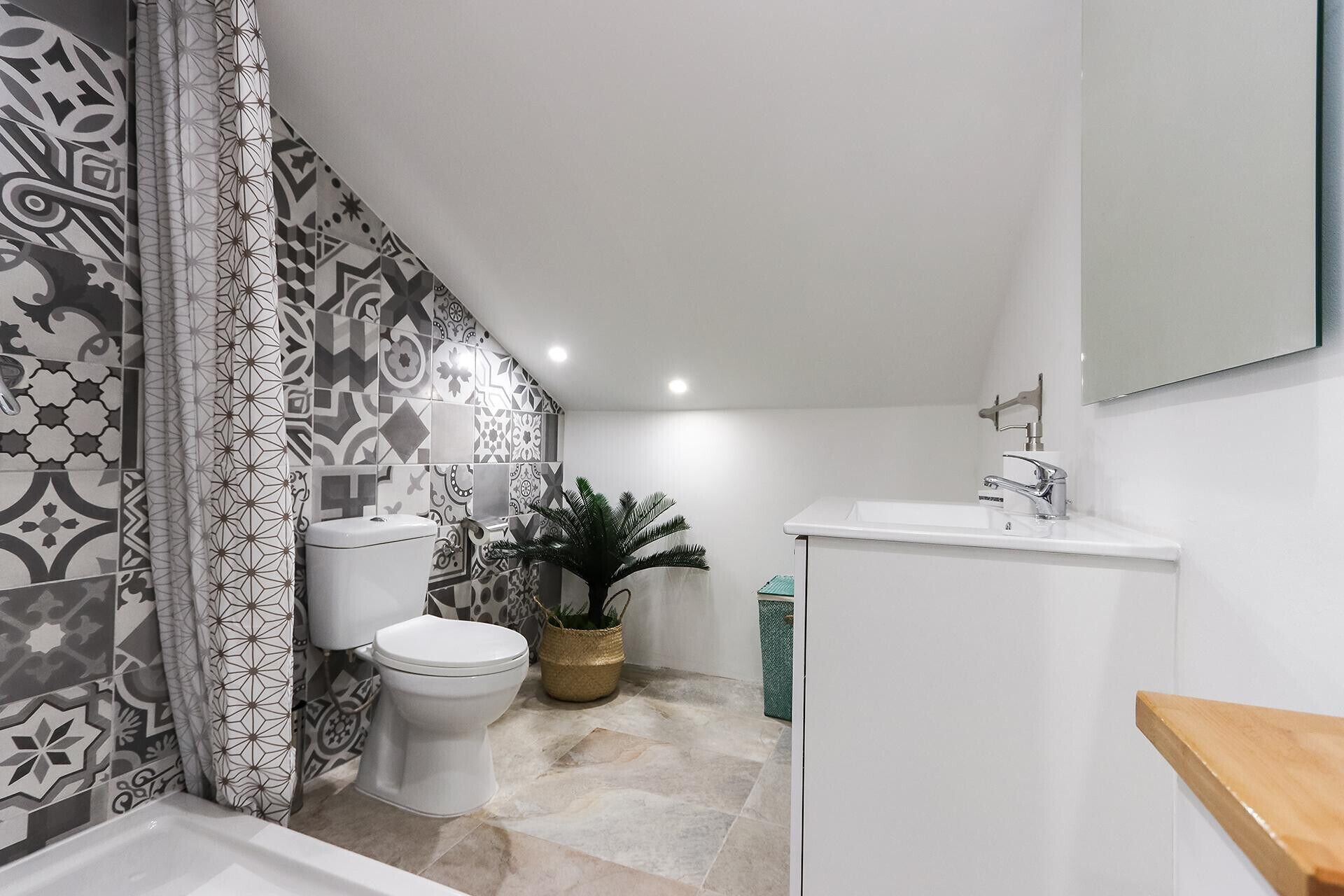 Een badkamer met betegelde vloer, toilet, wastafel en een plant in pot.