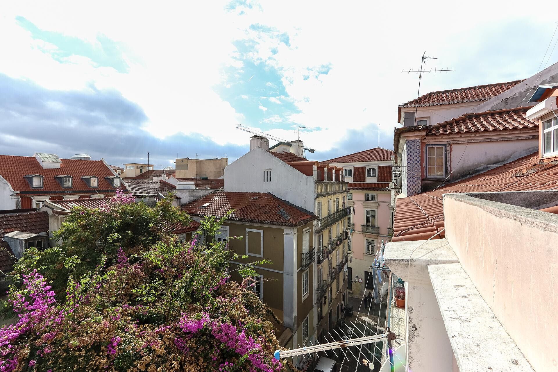 Vista de uma rua estreita com edifícios com telhados de barro e varandas.