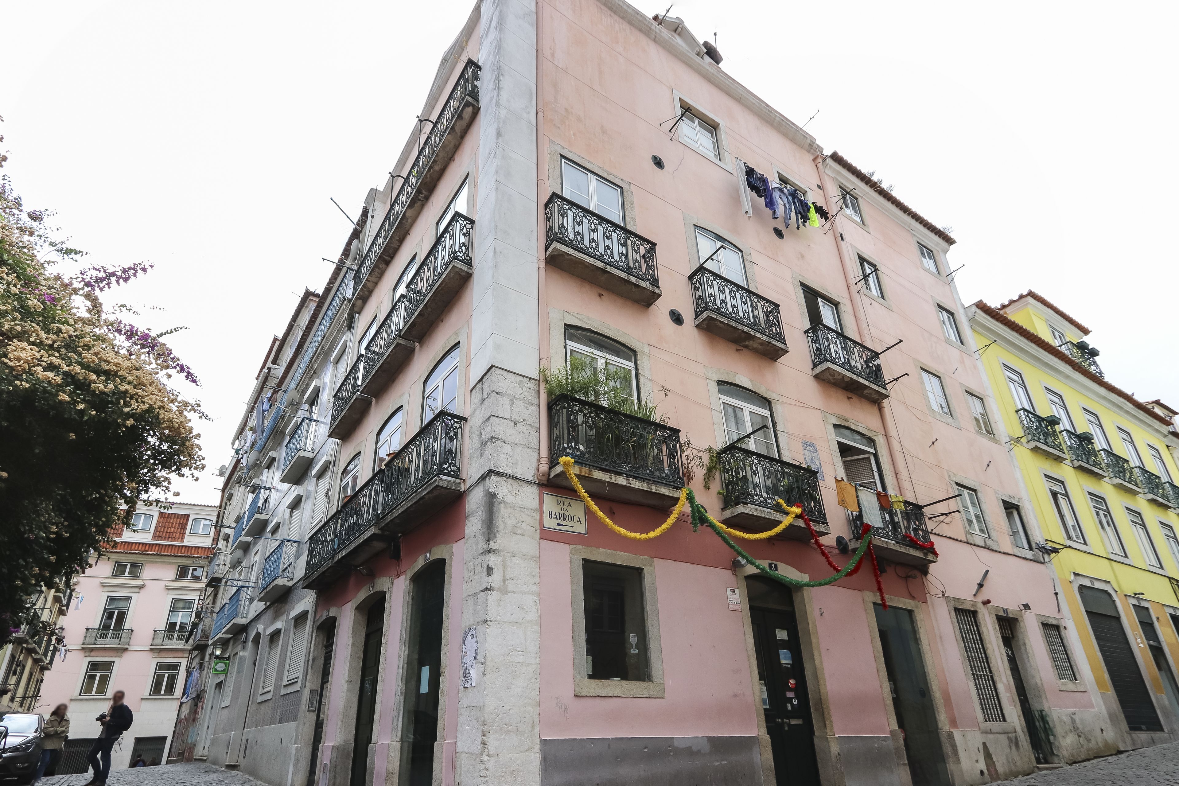 A multi-story building with balconies, a sign indicating 'BARBOSA', and a cobblestone street.