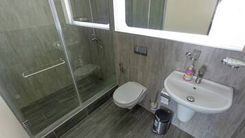Un baño moderno con ducha envuelta en vidrio, inodoro y lavamanos.