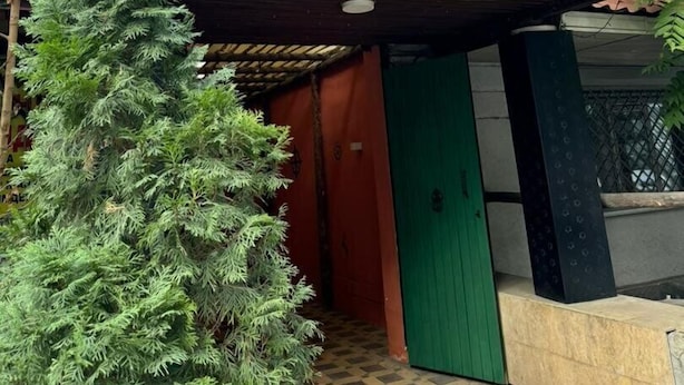 A sign for a hotel with a wooden structure and a green door. - Koisha Hostel (Bishkek)