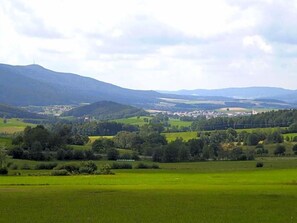 Paesaggio rurale con dolci colline, un piccolo insediamento e cielo sereno.