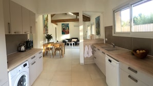 Una cocina moderna con lavadora, un lavamanos y un comedor con mesa y sillas.