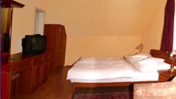 Un dormitorio con cama, escritorio con televisor, armario y alfombra.