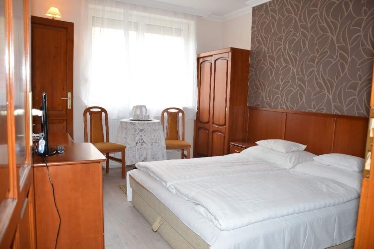 Ein Hotelzimmer mit Bett, Schreibtisch mit Computer, zwei Stühlen, einem kleinen Tisch mit Wasserkocher und einem Kleiderschrank.