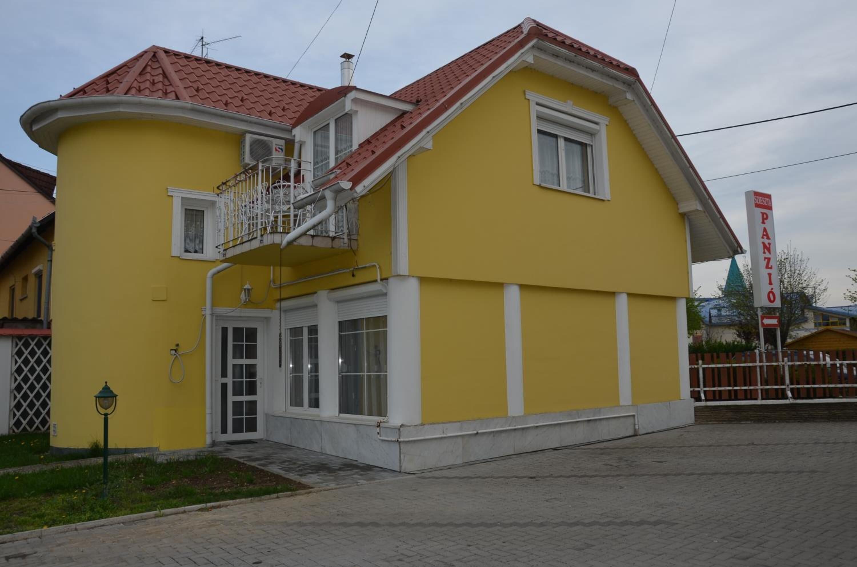 Un bâtiment jaune avec un toit rouge, un balcon et une enseigne sur laquelle on peut lire « PANZI ».