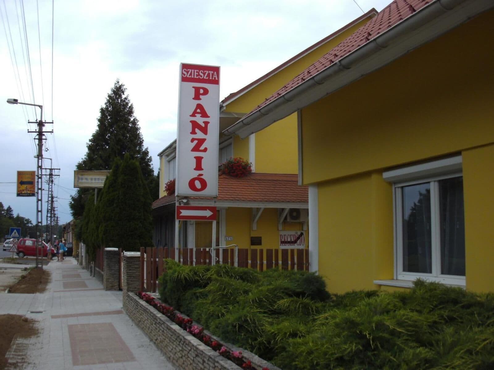 A yellow building with a sign reading "SZLIESZT PANZIO" and a directional arrow.