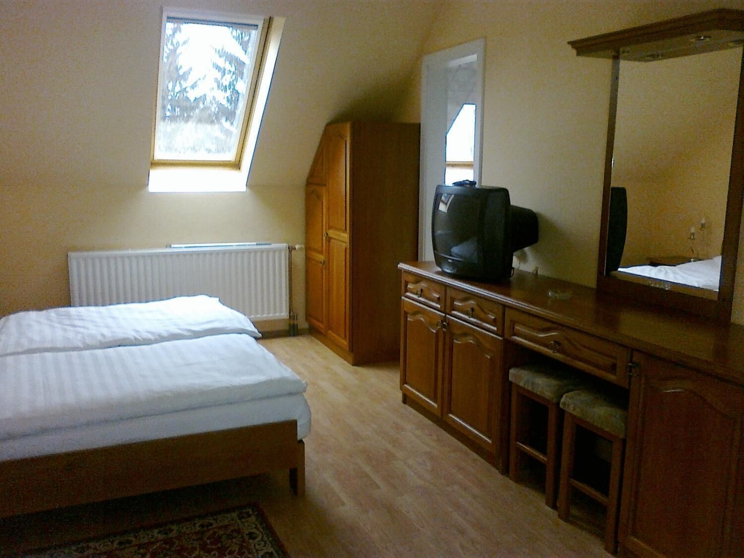 A bedroom with a bed, a dresser, a television, and a window.