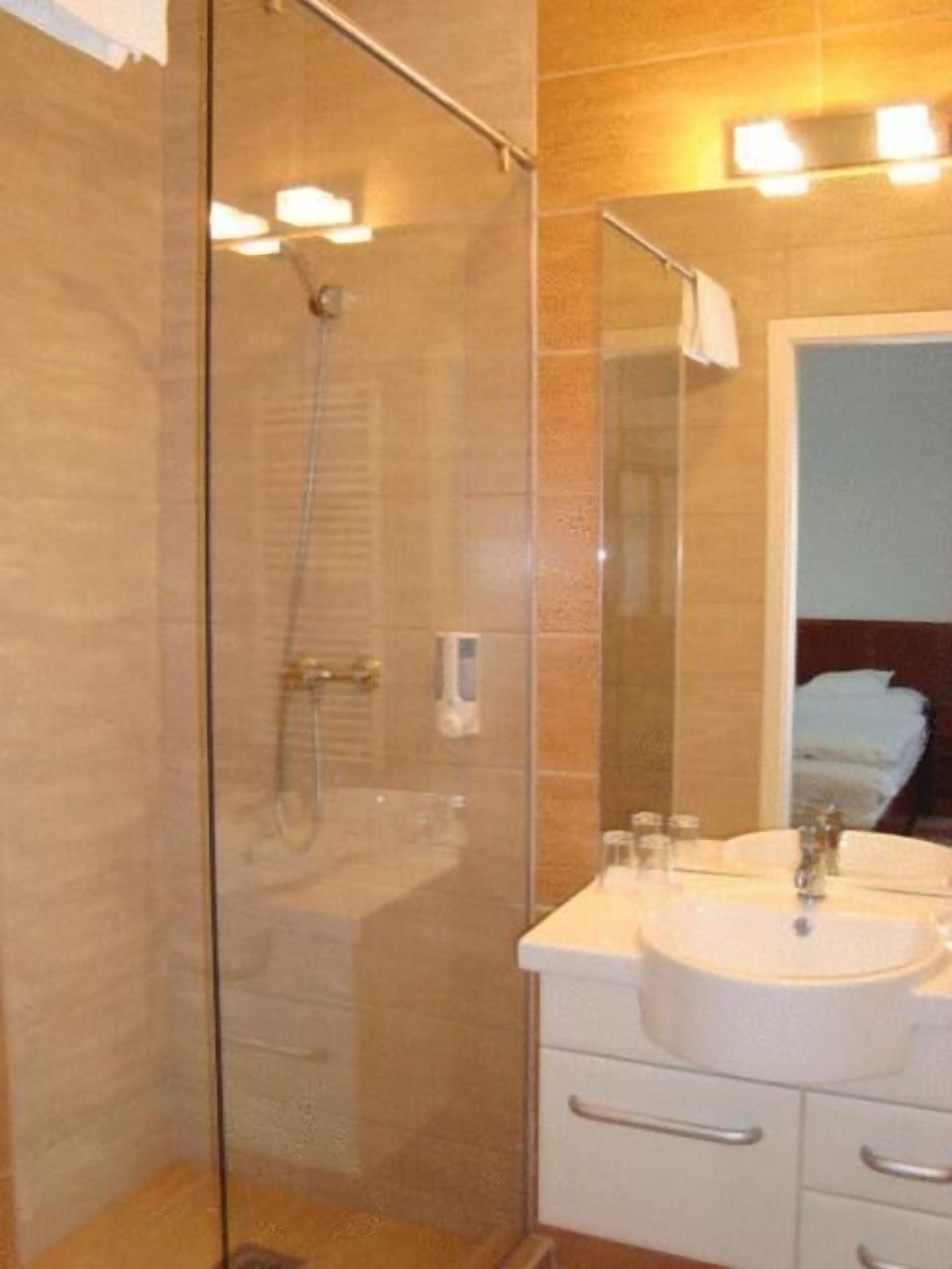 Un baño moderno con ducha envuelta en cristal, un lavabo blanco y un espejo.
