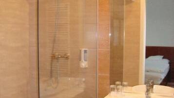 Un baño moderno con ducha envuelta en cristal, un lavabo blanco y un espejo.