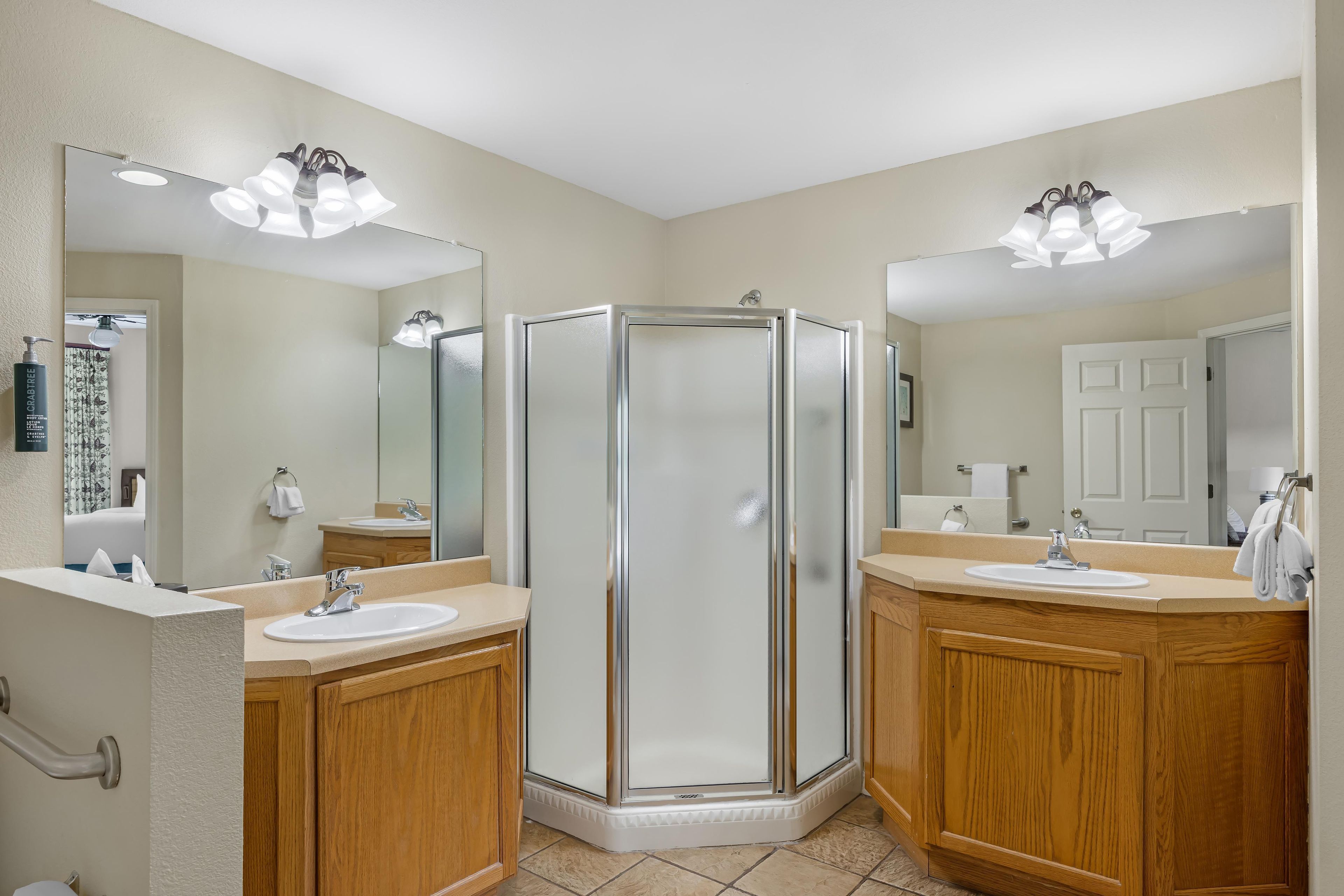 A modern bathroom with two sinks, a shower enclosure, and large mirrors.