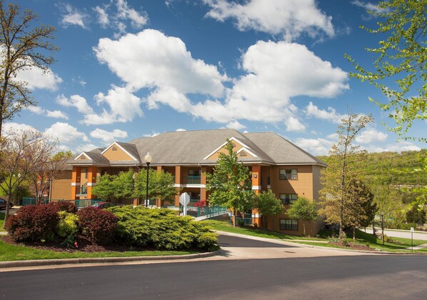 A multi-story hotel with a central courtyard, balconies, and a parking area.