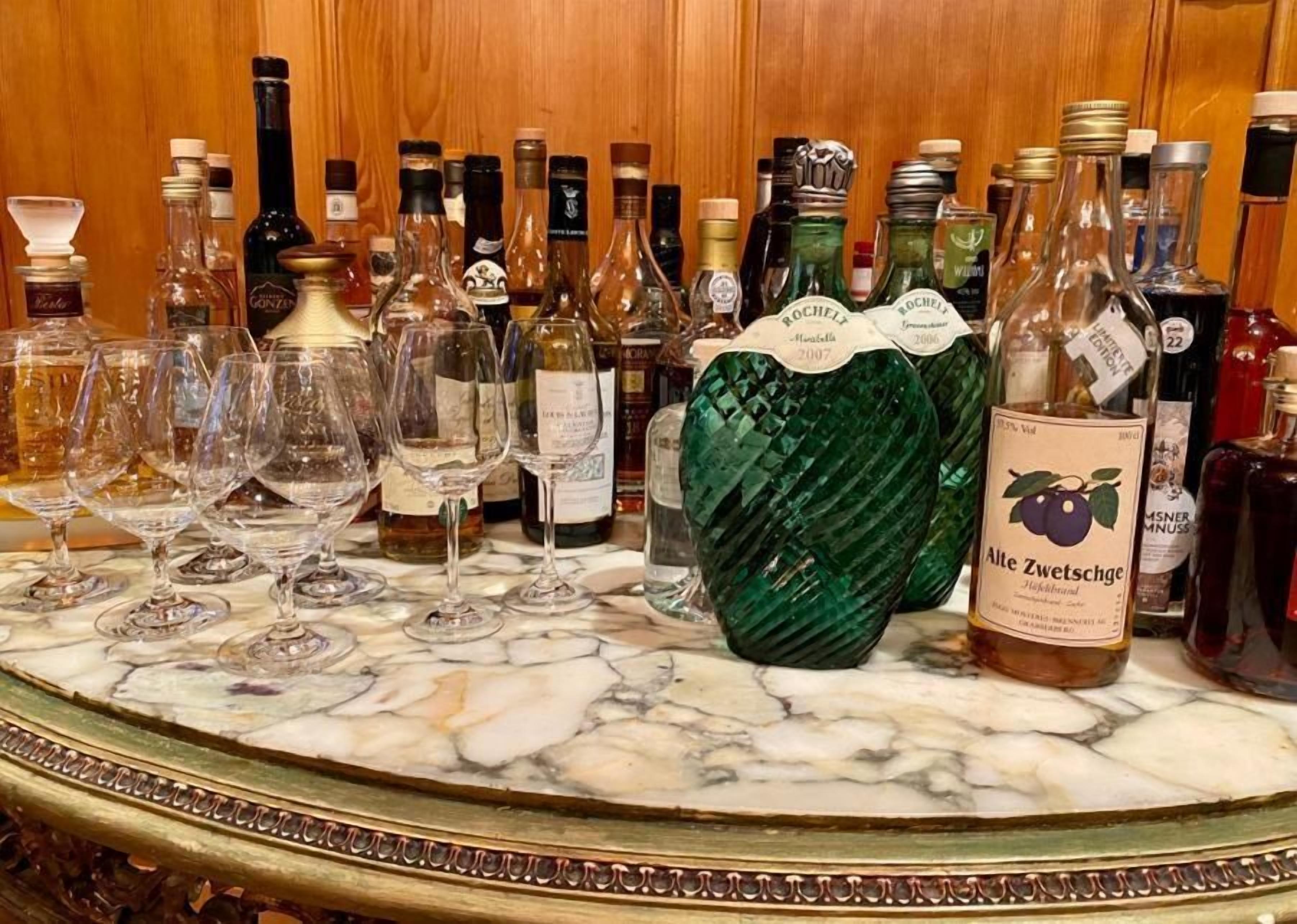 A bar area with various bottles and glasses on a marble countertop.