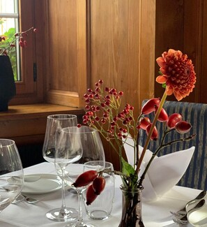 A table set for dining with clear glassware and a vase with red berries and a flower.
