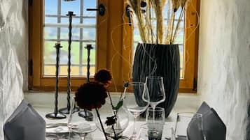 Une table à manger dressée avec plusieurs verres à vin, un vase contenant des plantes séchées et un chandelier.