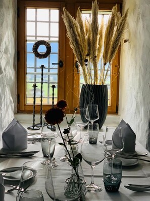 Una mesa de comedor con varias copas de vino, un jarrón con plantas secas y un candelabro.