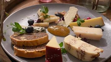 A plate of assorted cheeses and fruits on a table with candles.