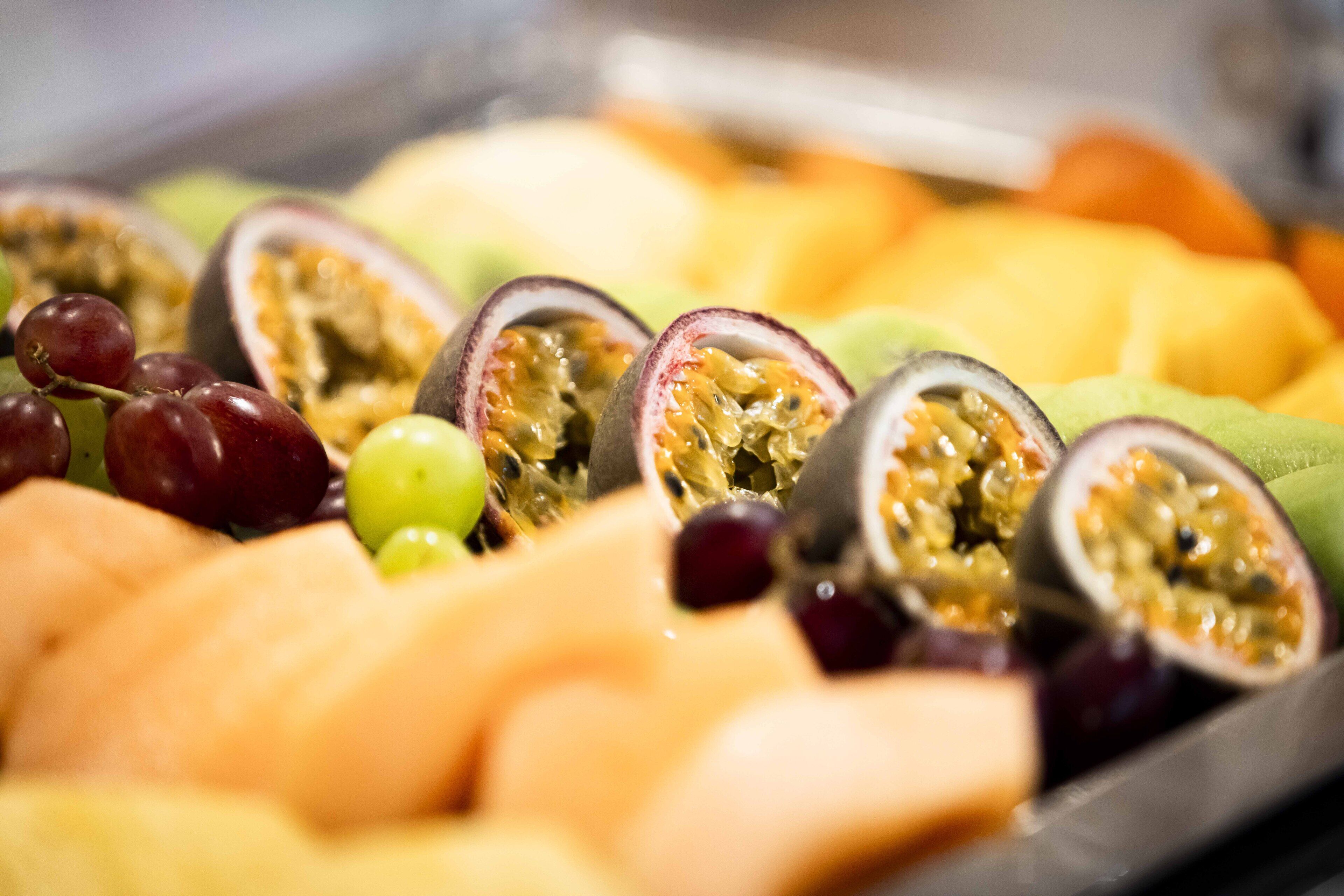A tray of assorted fruits including grapes, passion fruit, and melon slices.