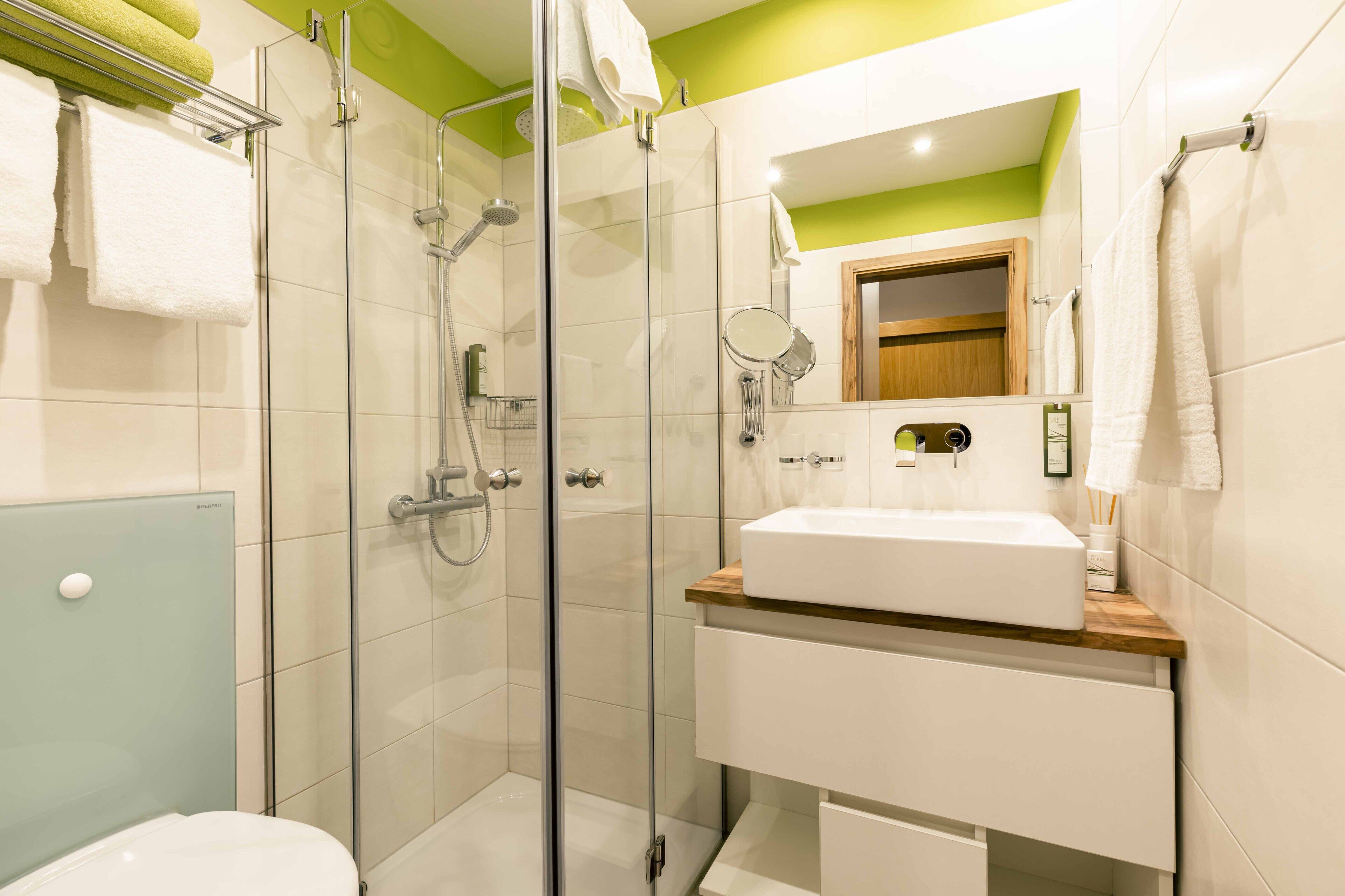 Une salle de bain moderne avec une douche à parois de verre, un lavabo blanc doté d’un plan de travail en bois et un miroir au-dessus du lavabo.