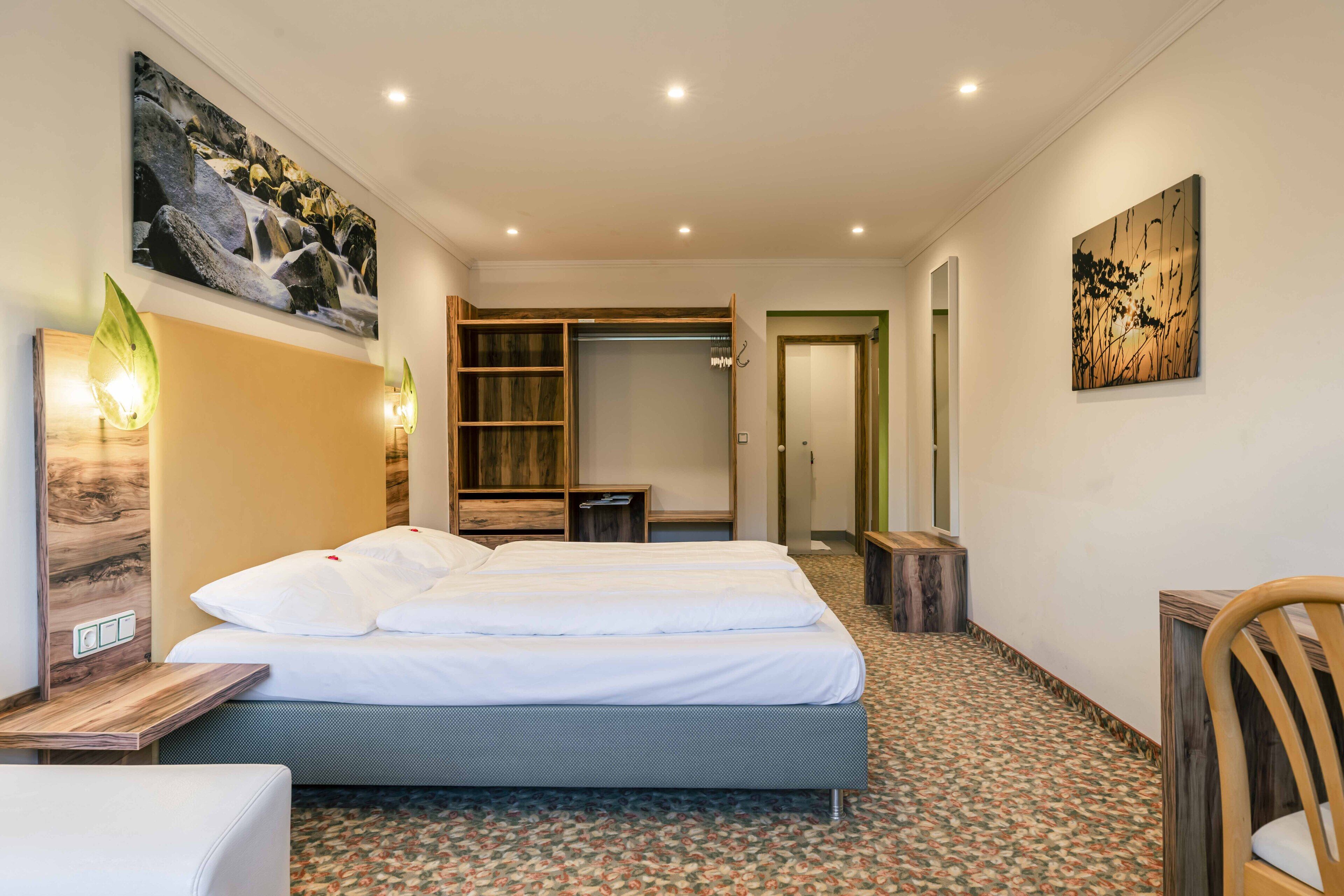 A hotel room with a bed, bedside tables, a wardrobe, and a mirror.