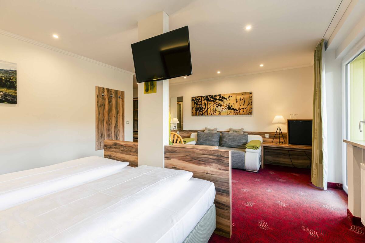 Une chambre d’hôtel moderne dotée d’un grand lit, d’un bureau avec un ordinateur et d’un téléviseur fixé au mur.