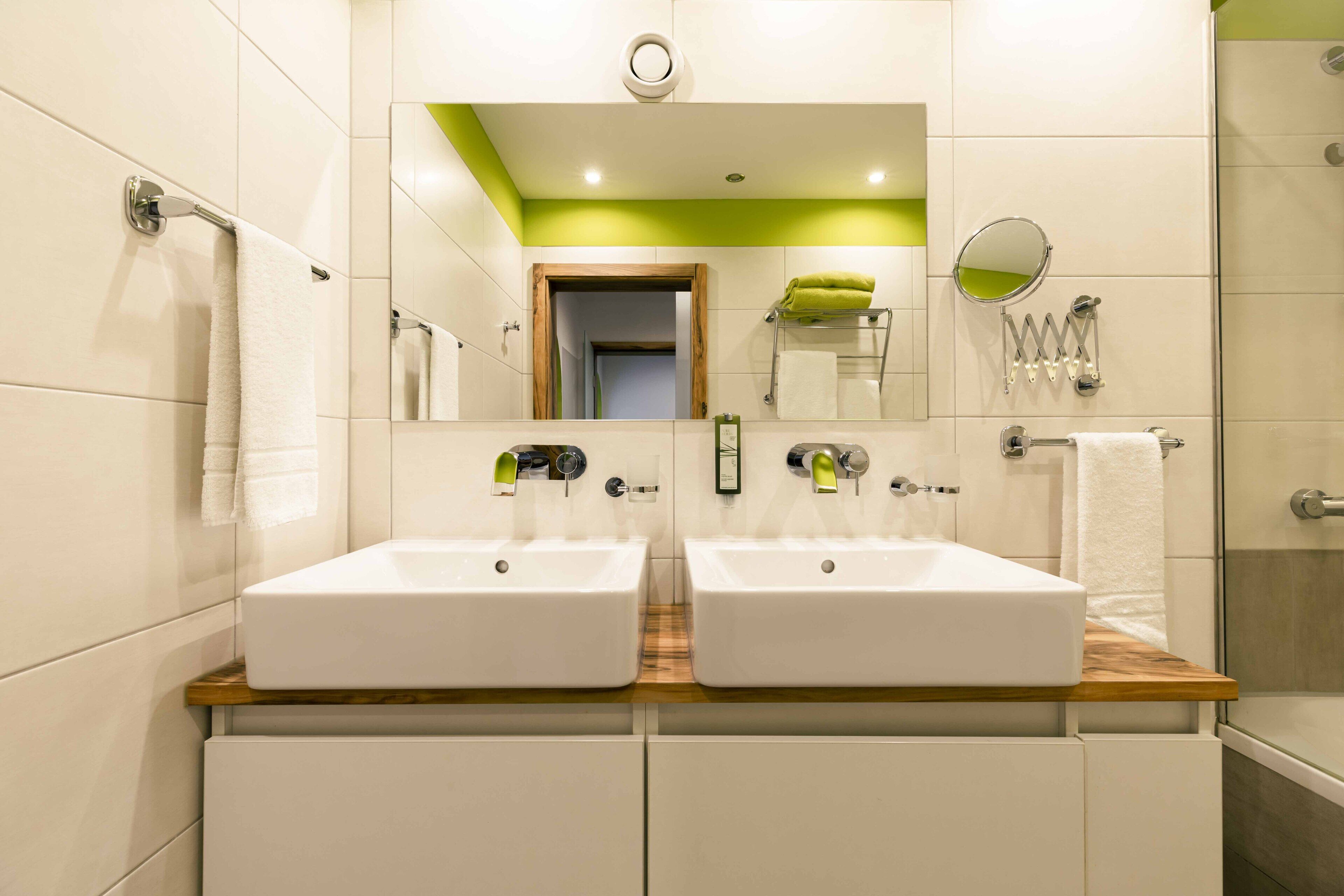A modern bathroom with two sinks, a mirror, and a shower.
