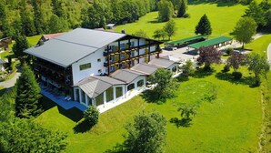 A large, multi-story building with a flat roof, surrounded by lush green fields and trees. - Garni GrünWies - Adults Only (Lohberg)
