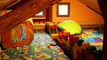 A playroom with a loft bed, a play tent, and a colorful play mat.