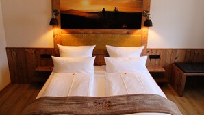 A double bed with white linens, two bedside tables, a wooden headboard with a sunset painting, and two wall-mounted lamps. - Bayerische Gastwirtschaft Dimpfl-Stadl (Lam)