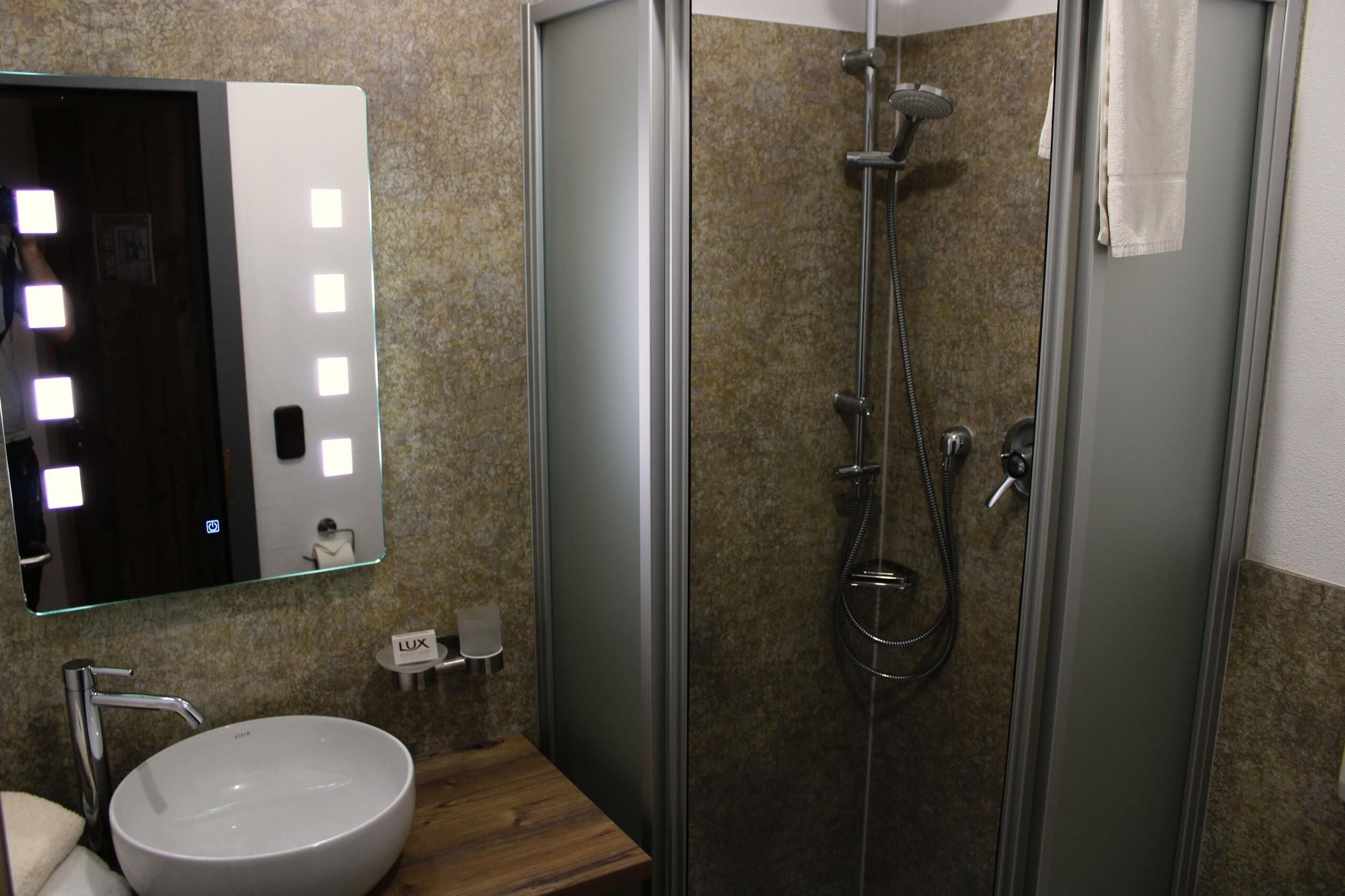 A bathroom with a glass-enclosed shower, a sink with a mirror, and a towel rack.