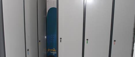 A row of lockers with a blue snowboard leaning against one.