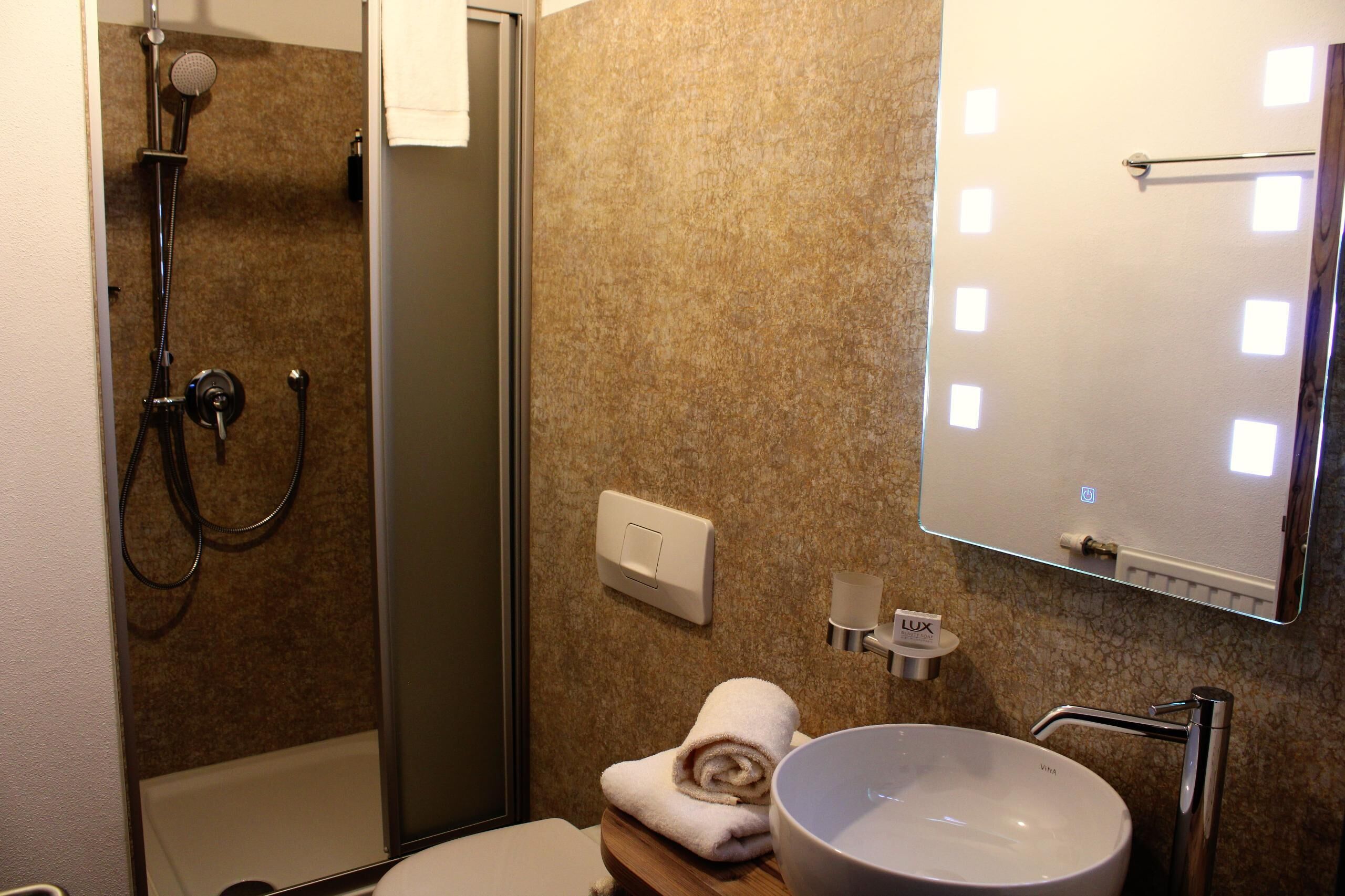 Un baño con ducha, lavabo y espejo.