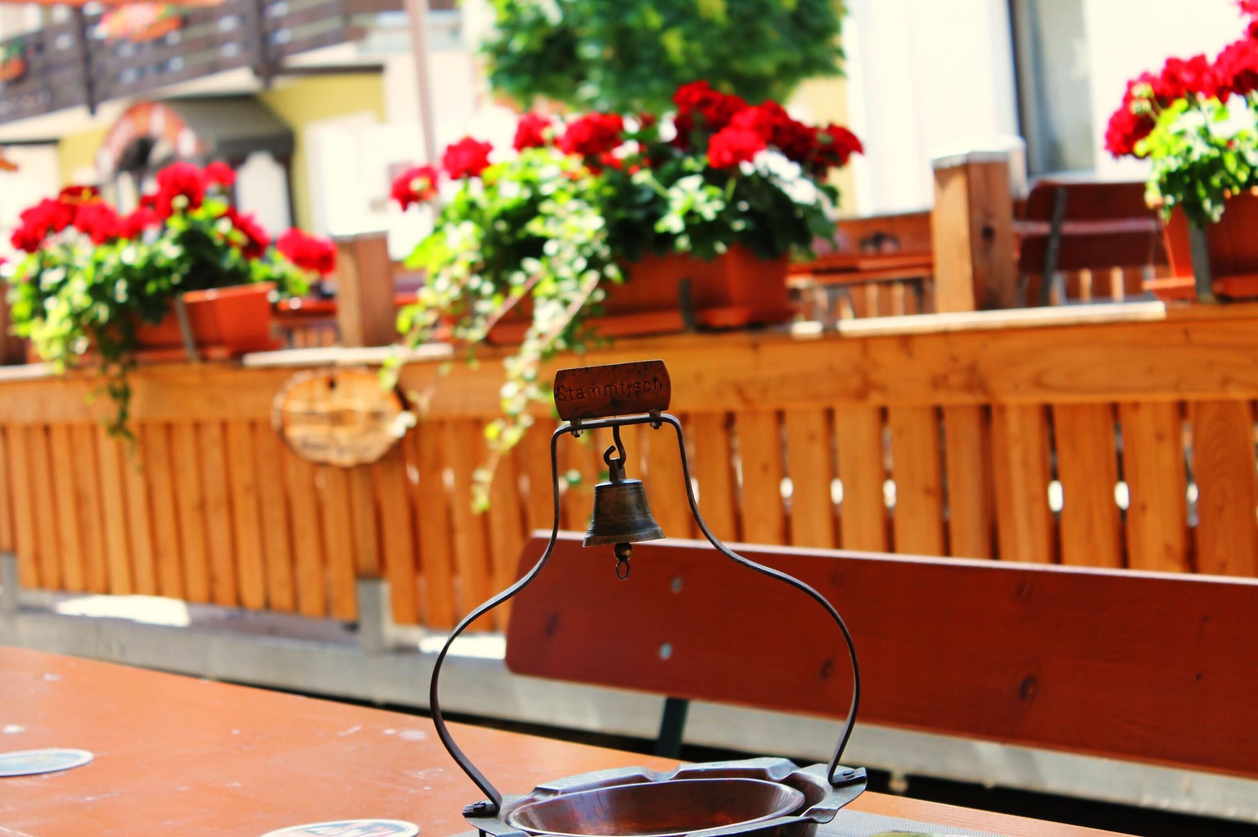 A wooden bench with a metal bell and a metal tray in front of it.