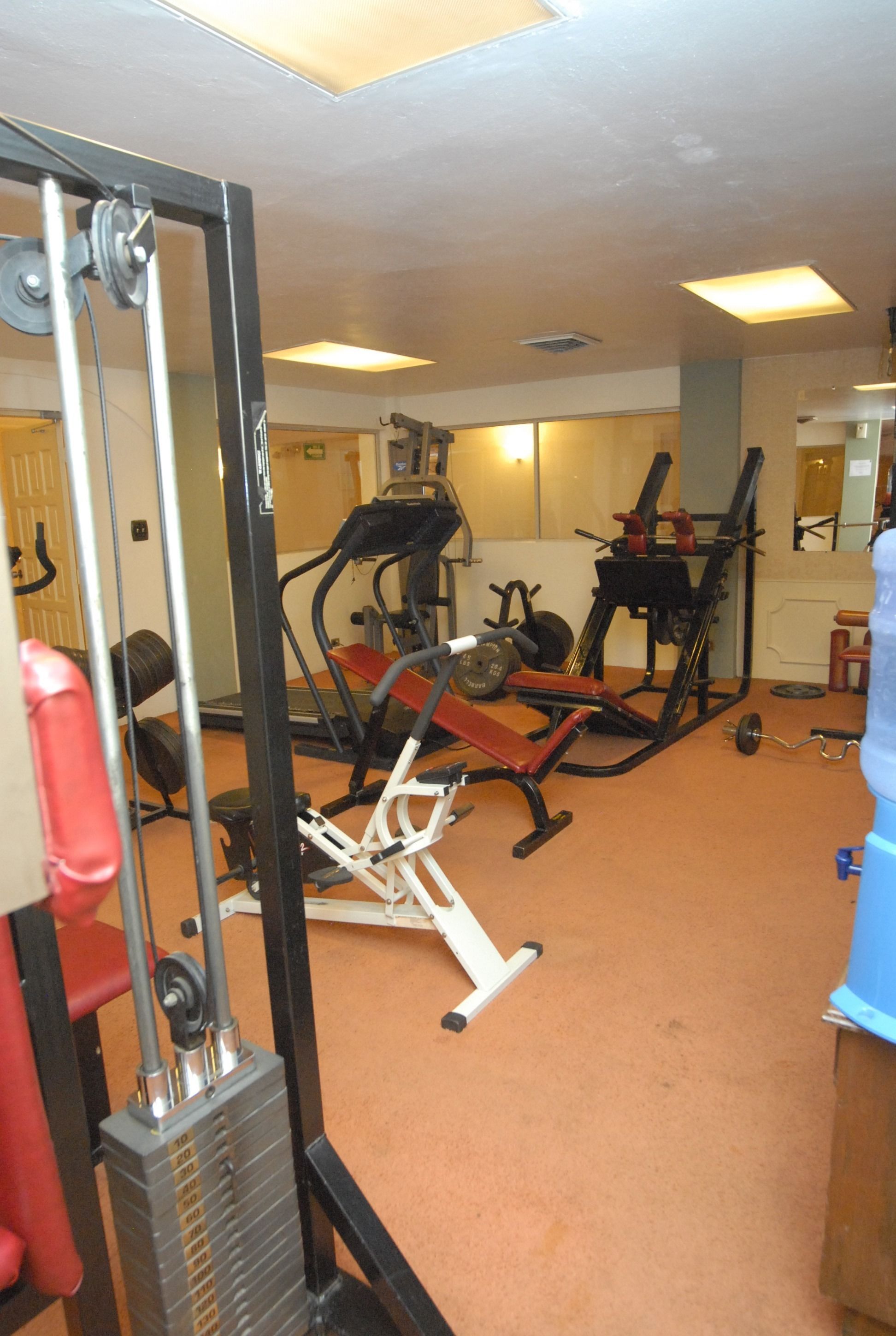 A gym with exercise equipment, a water dispenser, and a mirror.