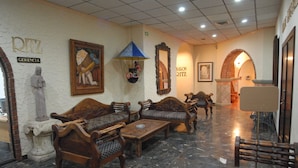 A lobby with wooden furniture, a statue, and a mirror.