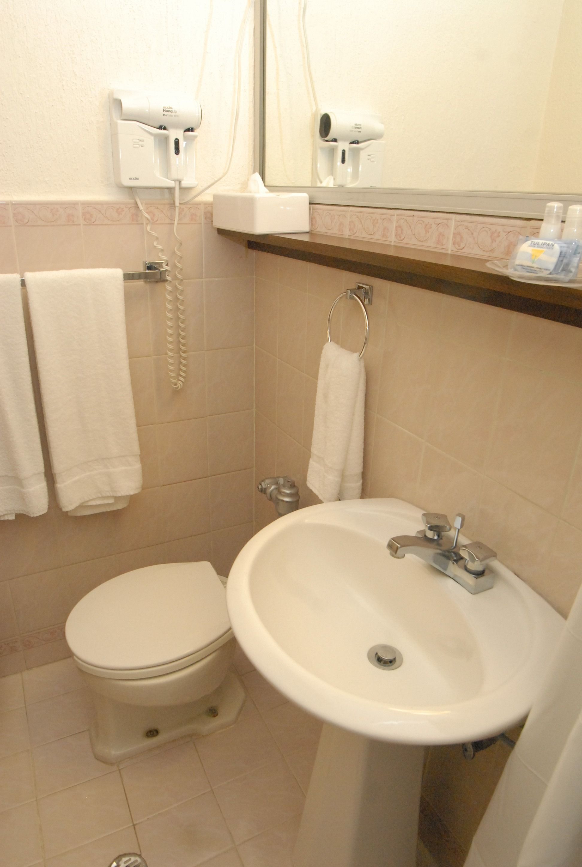 Une salle de bain équipée de toilettes, d’un lavabo et d’un porte-serviettes.