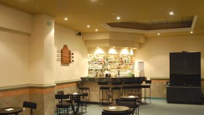 A bar area with multiple seating arrangements, a counter with a variety of bottles, and a television screen.