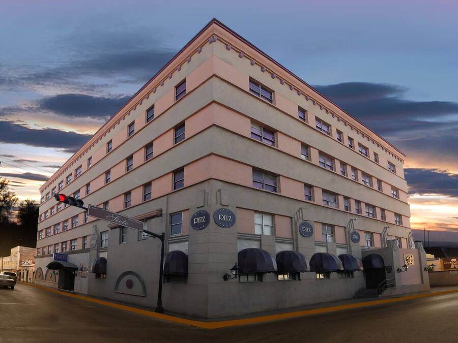 Un hotel de varios pisos con un diseño arquitectónico clásico, que cuenta con una entrada destacada en esquina y varios balcones.