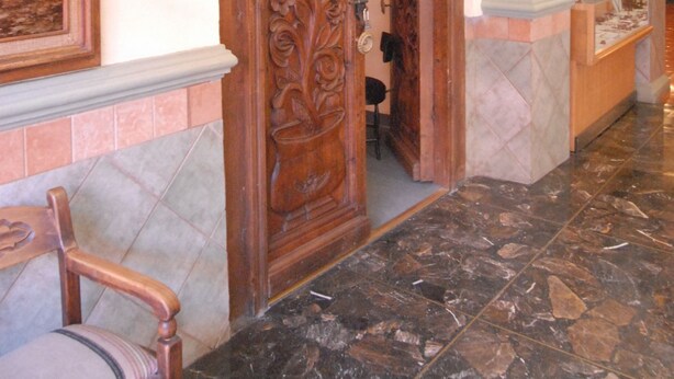 A lobby with a wooden door labeled 'Ritz Vivo - Piano - Bar'.
