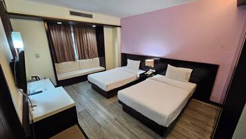 A hotel room with two beds, a desk, a mirror, and a window with curtains.