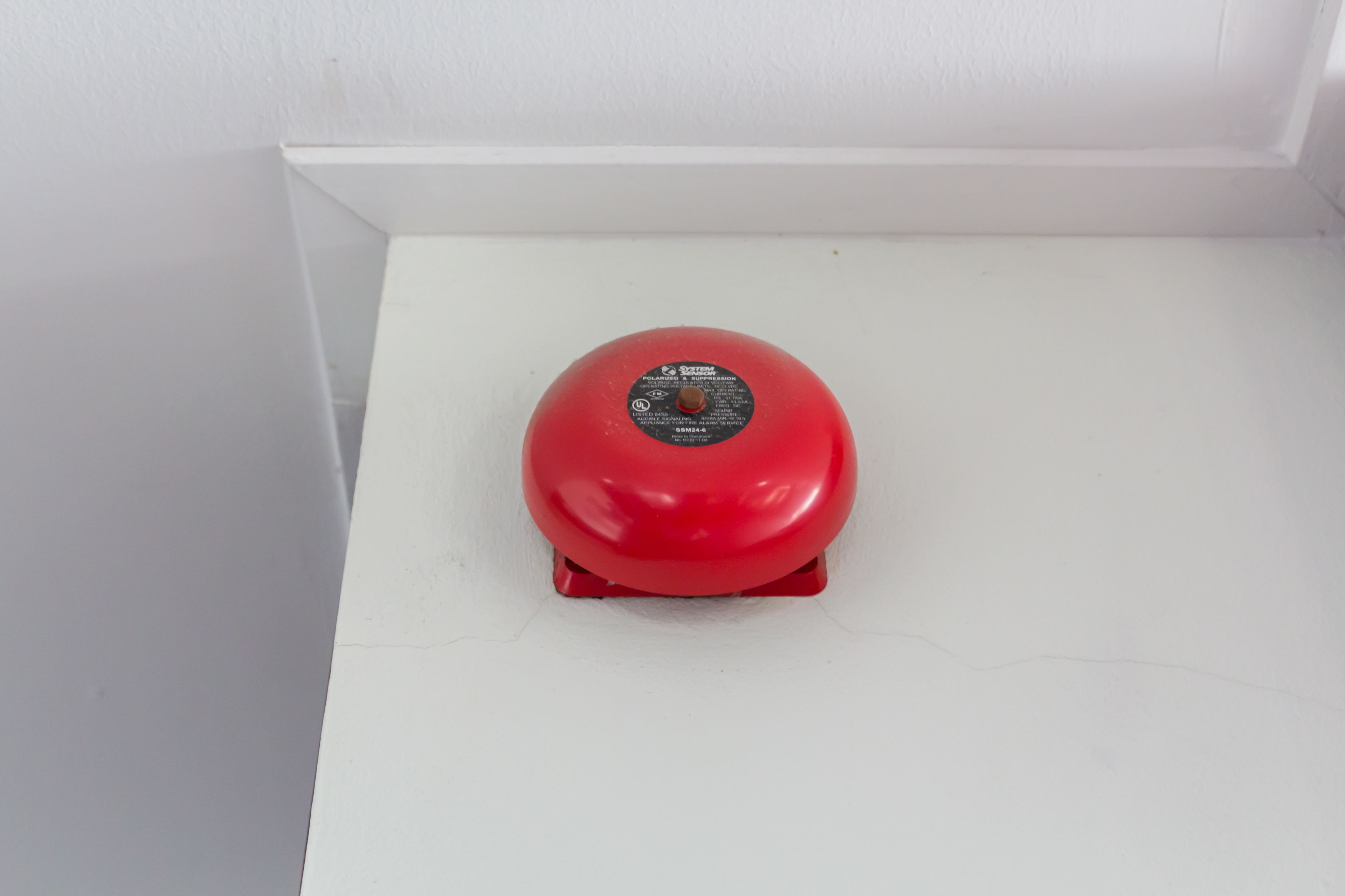 A red fire alarm on a white surface.