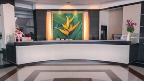 A reception desk with a large plant and a vase of flowers. - City Park Hotel (Nakhon Ratchasima)